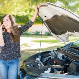 Woman talking to a mobile mechanic while standing by broke down car at roadside